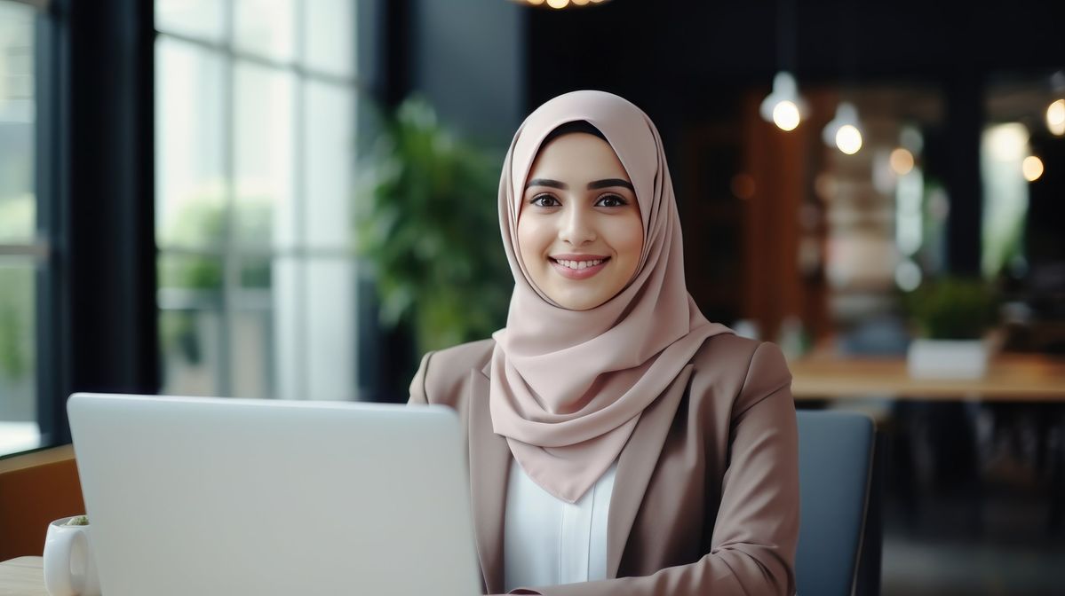 young muslim woman wearing a hijab is working on a laptop in the office